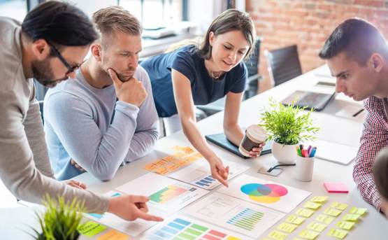 Group of people around a table with graphs and diagrams and post its