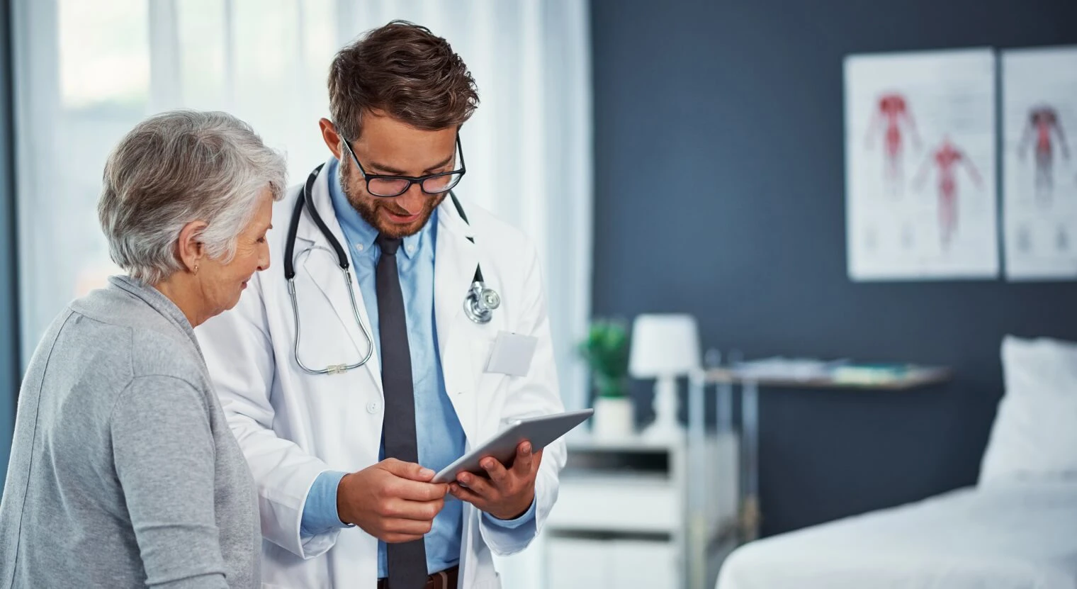 A medical professional talks to a patient whilst looking at a tablet 