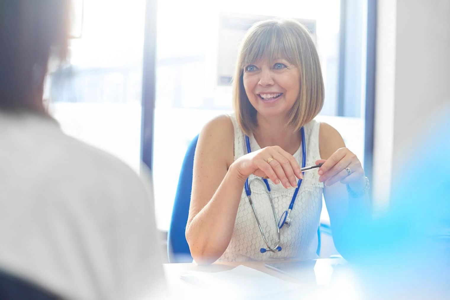 a medical professional smiles as she talks to a patient 