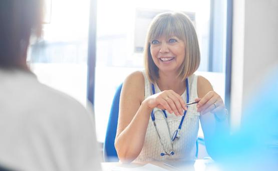 a medical professional smiles as she talks to a patient 
