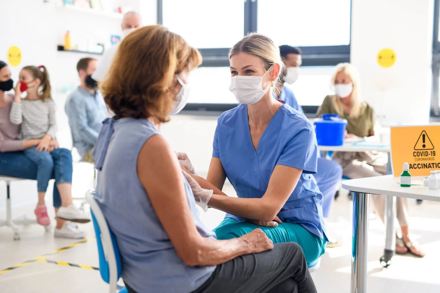 Woman with face mask getting vaccinated by female nurse