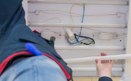 Image of electrician changing bulb in fluorescent strip light