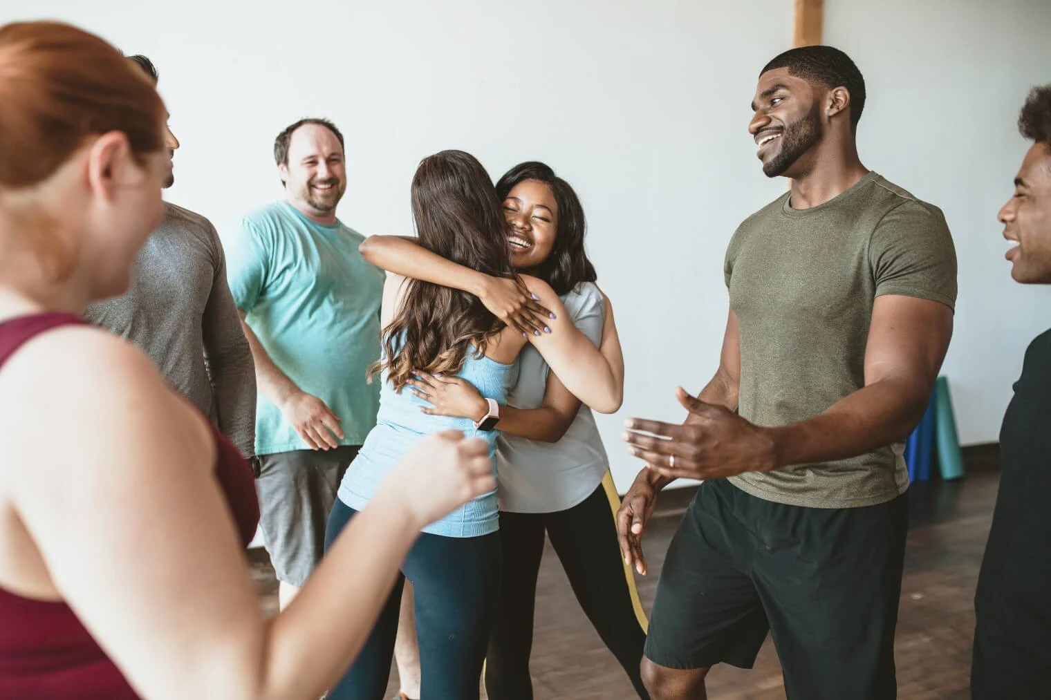 Stock image of a group of people in an exercise class where 2 women are hugging
