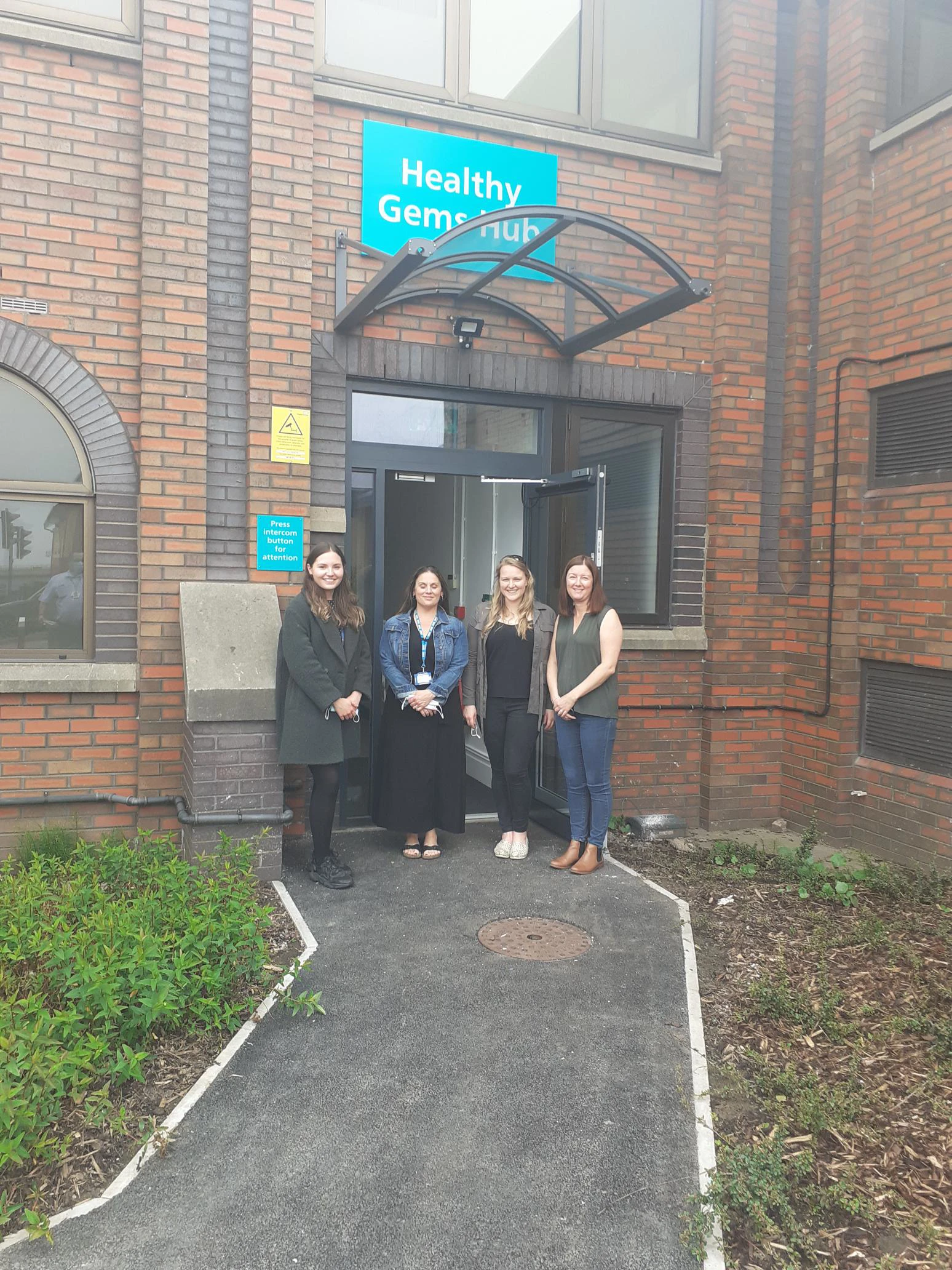 Four women standing at the front of Healthy Gems Hub, smiling
